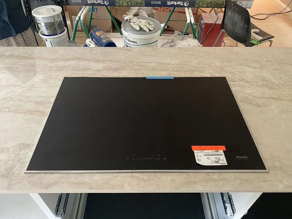 Infälld Miele induktionshäll i en polerad Dekton Arga köksbänkskiva i ett kök i Fjärås.