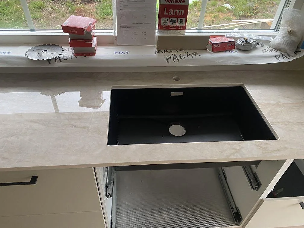 Polerad Dekton Arga köksbänkskiva med underlimmad svart diskho framför fönster i ett kök i Fjärås.