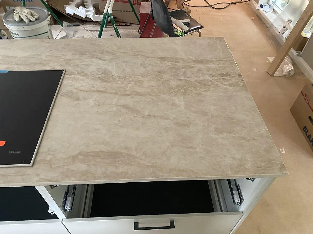Köksö i cremebeige Dekton Arga med Miele induktionshäll, polerad yta, i ett kök i Fjärås.