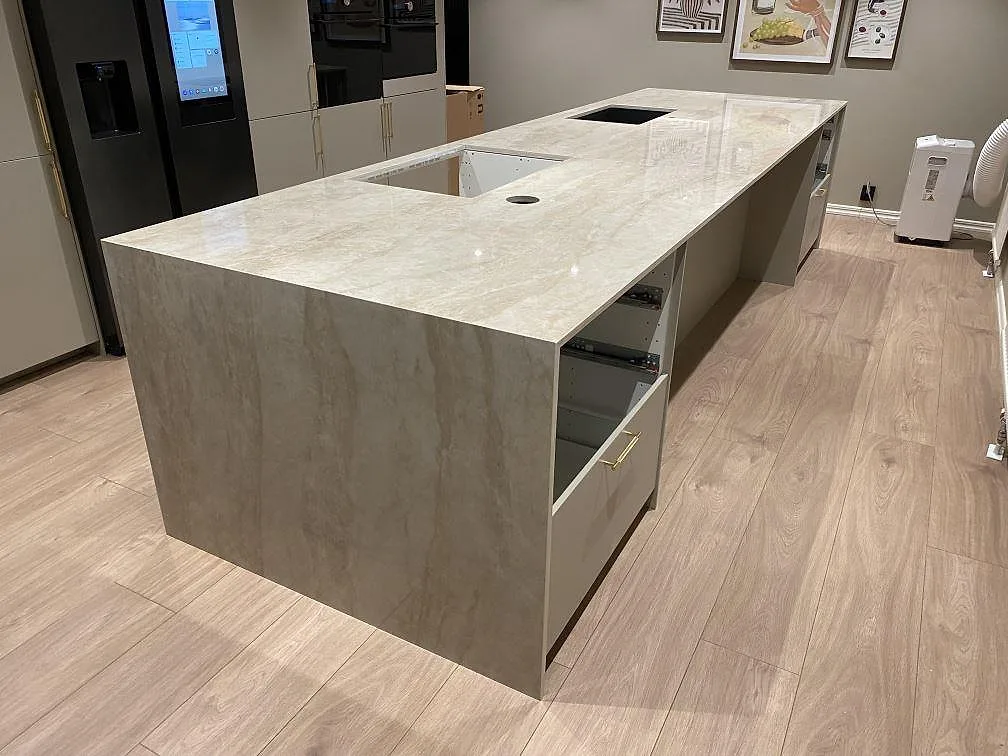 Köksö i polerad Dekton Arga med cremebeige ådring, svart diskho och förberett hällurtag i ett kök i Fjärås.