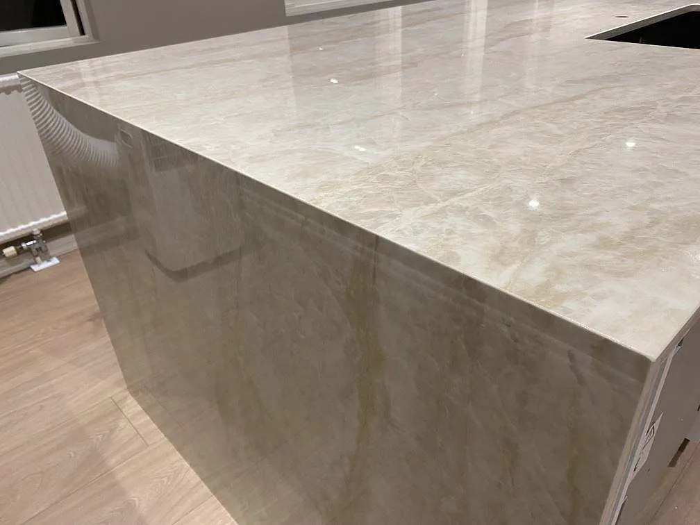 Detalj av stenklädd gavel och blank kant på köksbänkskiva i polerad Dekton Arga keramik i Fjärås.