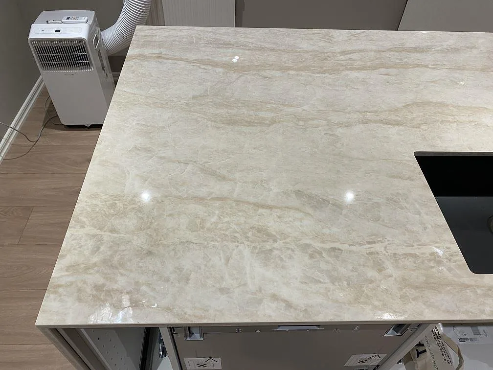 Närbild på polerad Dekton Arga keramikyta med cremebeige ådring bredvid den svarta diskhon i ett kök i Fjärås.