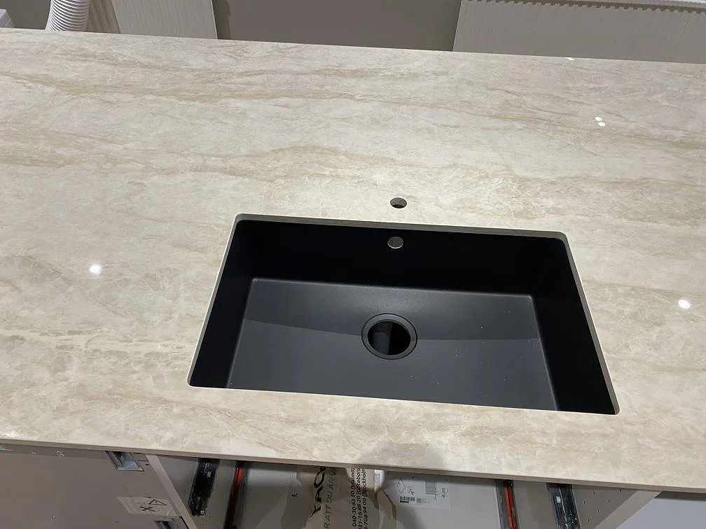 Svart underlimmad diskho i en polerad Dekton Arga köksbänkskiva med ljust ådrad keramikyta i Fjärås.