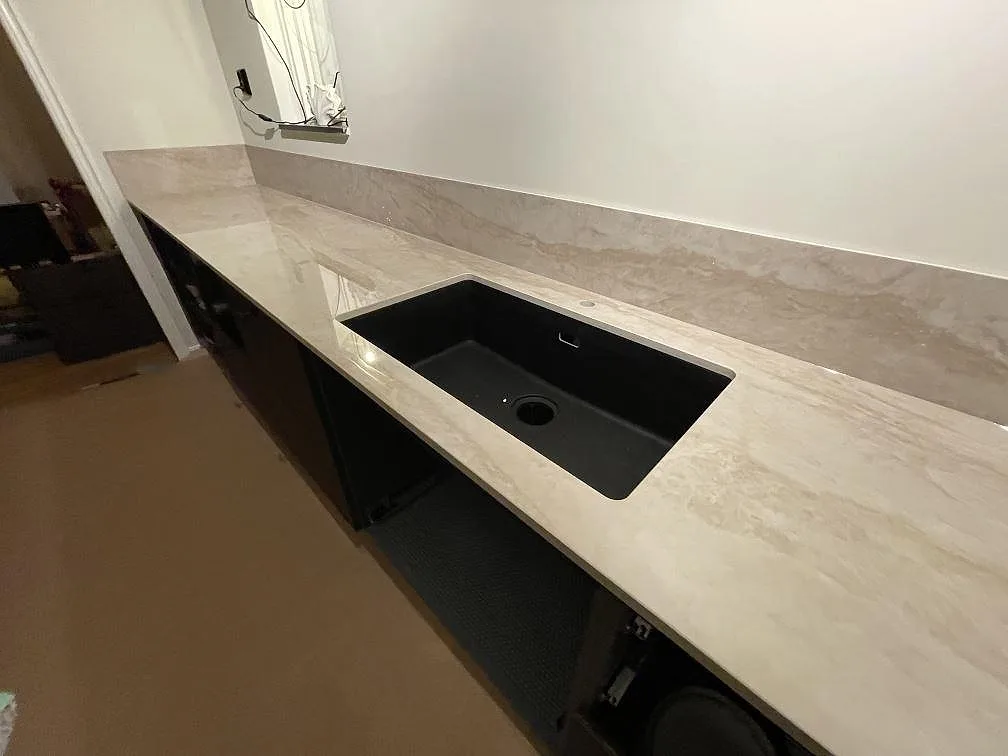 Underlimmad svart kompositdiskho i en cremebeige Dekton Arga bänkskiva, polerad keramik med ådring, i ett kök i Flen.