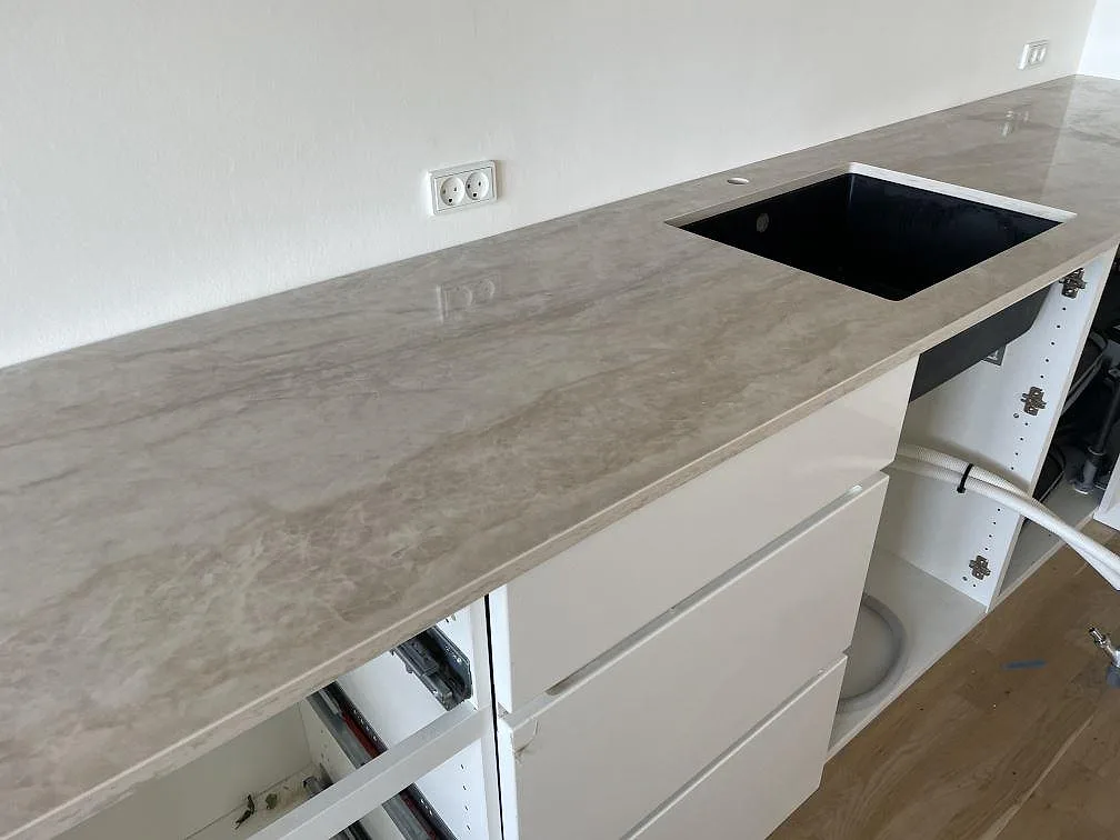 Polerad Dekton Arga köksbänkskiva med svart underlimmad diskho och ljus ådring mot vit vägg i Frederiksberg.