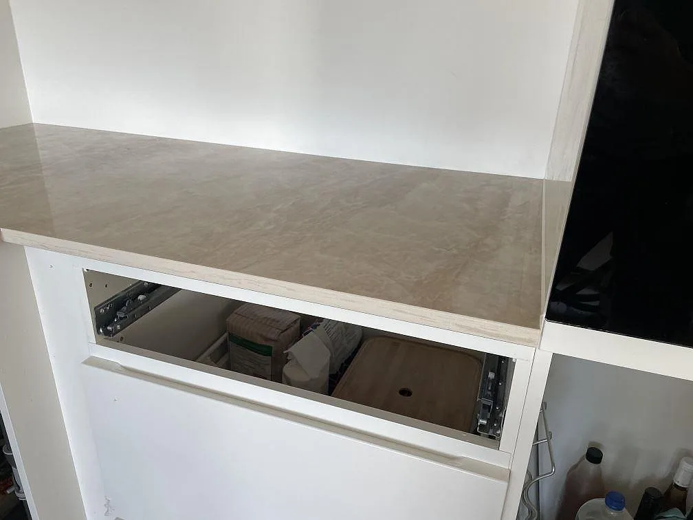 Rak bänkdel i polerad Dekton Arga keramik bredvid högskåp och vit köksinredning i Frederiksberg.