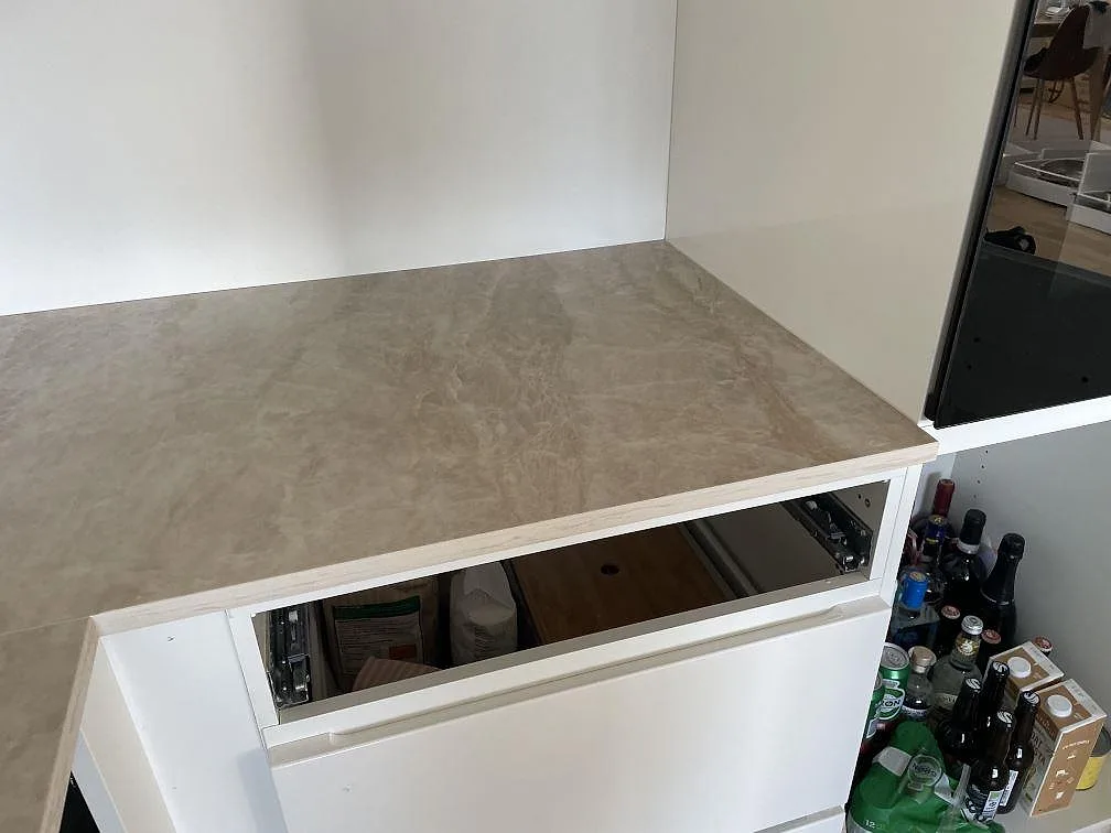 Sidosektion av polerad Dekton Arga bänkskiva på vita köksstommar under montering i Frederiksberg.
