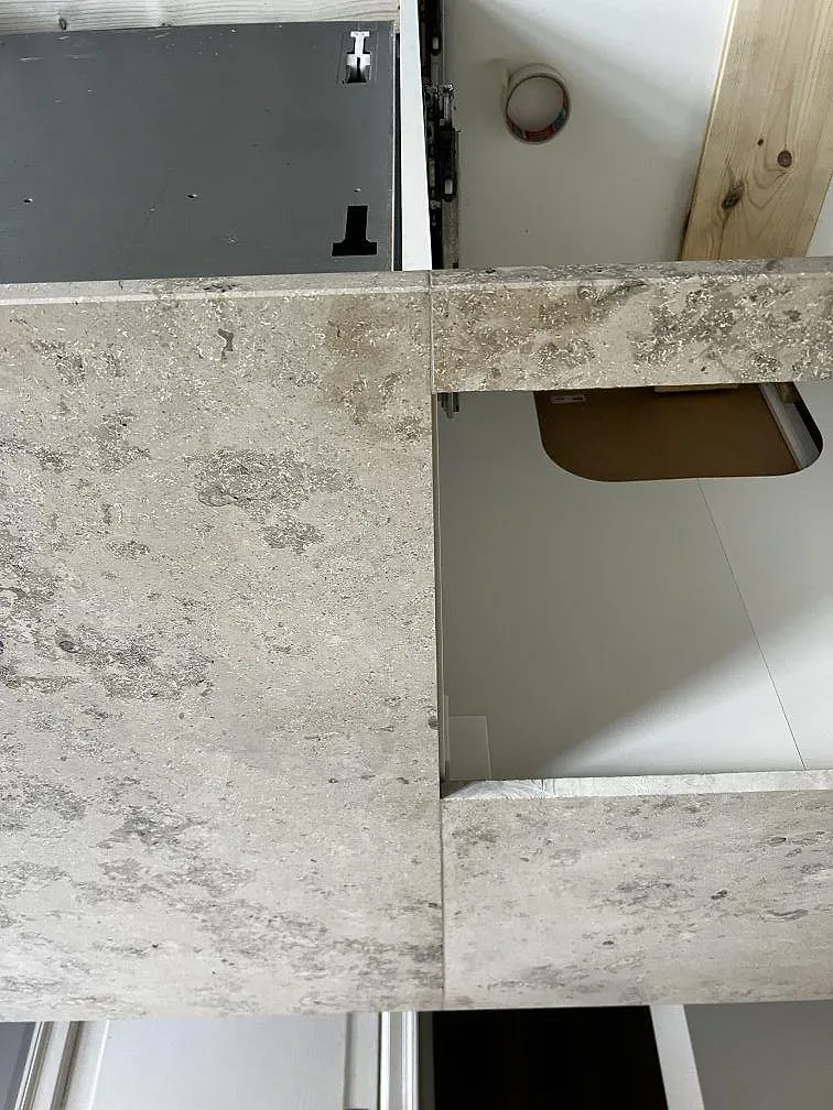 Köksbänkskiva och köksö i ljus gråmelerad Dekton Arga, polerad, i ett kök under montering i Frederiksberg.