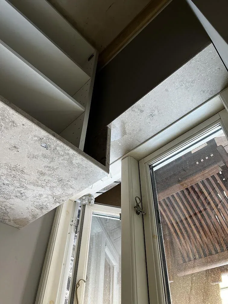 Köksbänkskiva i polerad Dekton Arga vid fönstret, monterad ovanpå öppna stommar i ett kök i Frederiksberg.