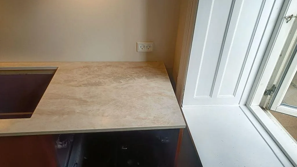 Närbild av polerad Dekton Arga bänkskiva med svart häll och stänkkant i ett kök i Frederiksberg.