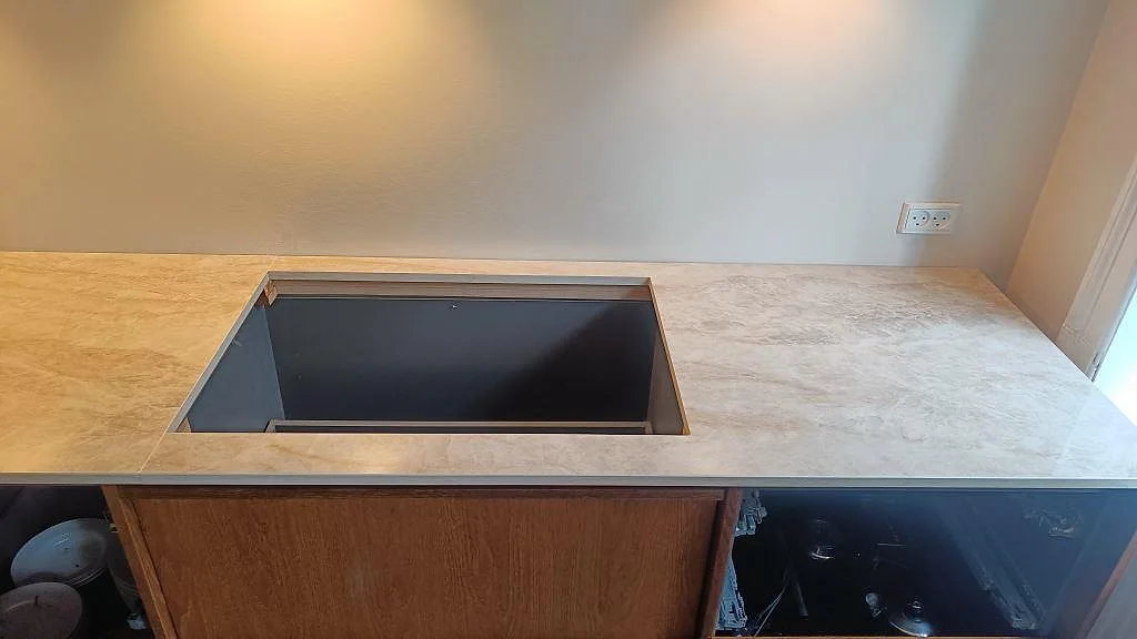 Detalj av bänkskiva i polerad Dekton Arga, keramik, med häll och synlig skarv under montering i Frederiksberg.