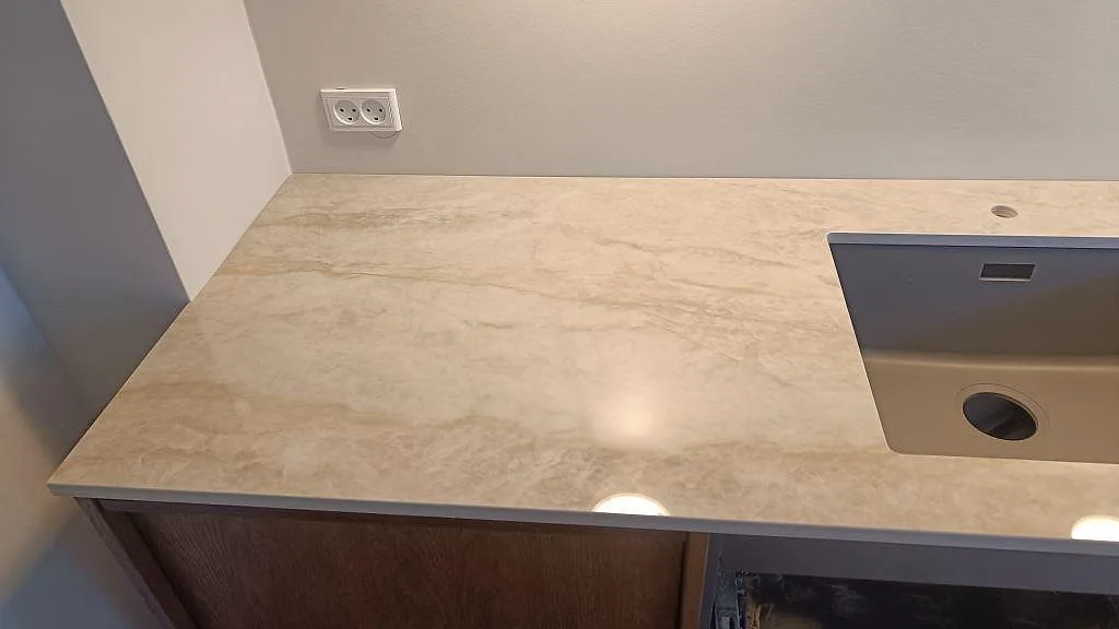 L-formad köksbänkskiva i polerad Dekton Arga, keramik, med svart underlimmad diskho vid fönster i Frederiksberg.