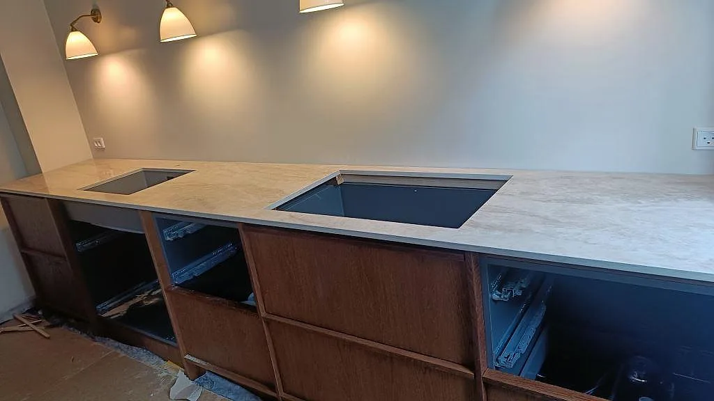 Köksbänkskiva i polerad Dekton Arga med svart häll, uppvikt stänkkant och öppen vit köksstomme i Frederiksberg.