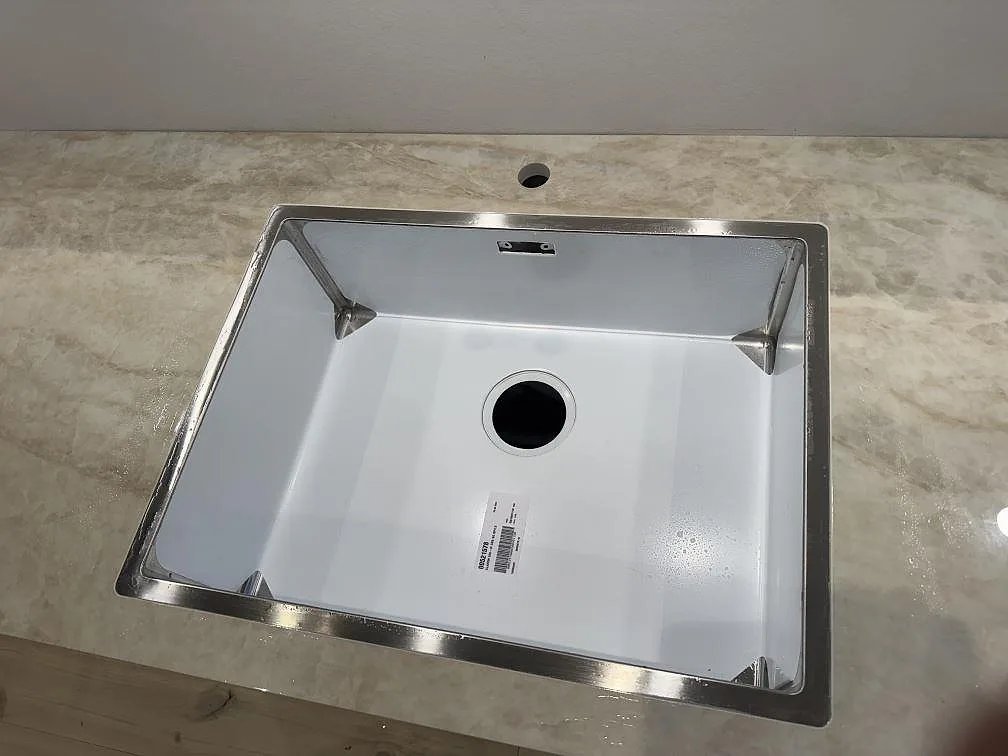 Närbild på diskhozonen i polerad Dekton Arga, ljus keramisk bänkskiva med blank yta och marmorerad teckning i Frederiksberg.