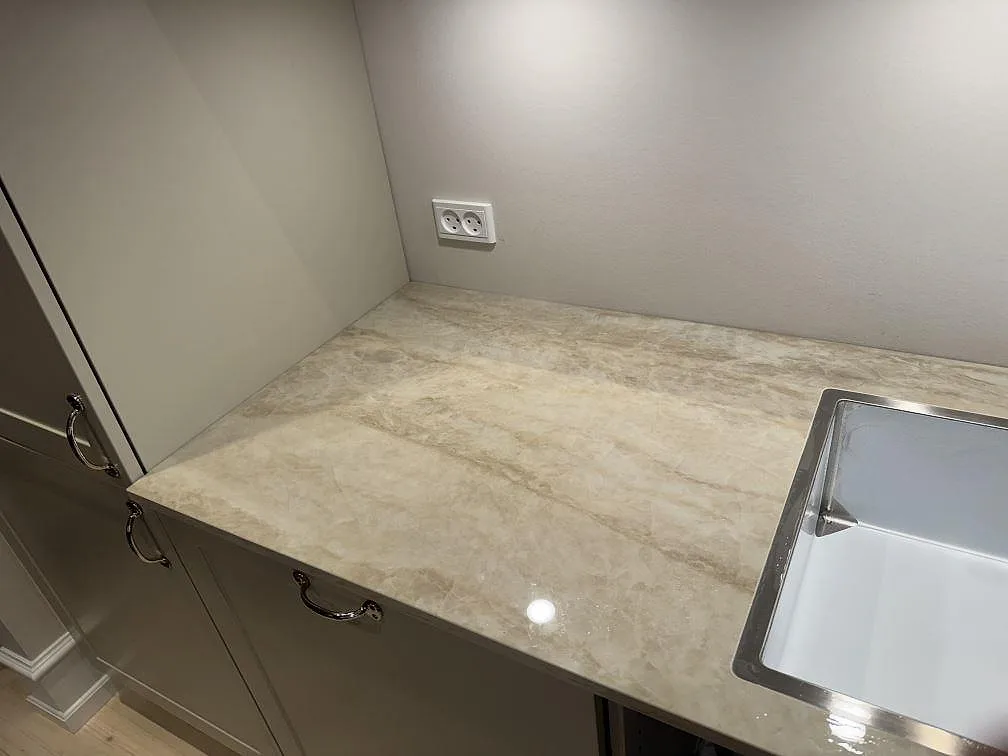 Väggnära köksbänkskiva i polerad Dekton Arga med ljus marmorerad yta, köksluckor och diskho vid sidan i Frederiksberg.