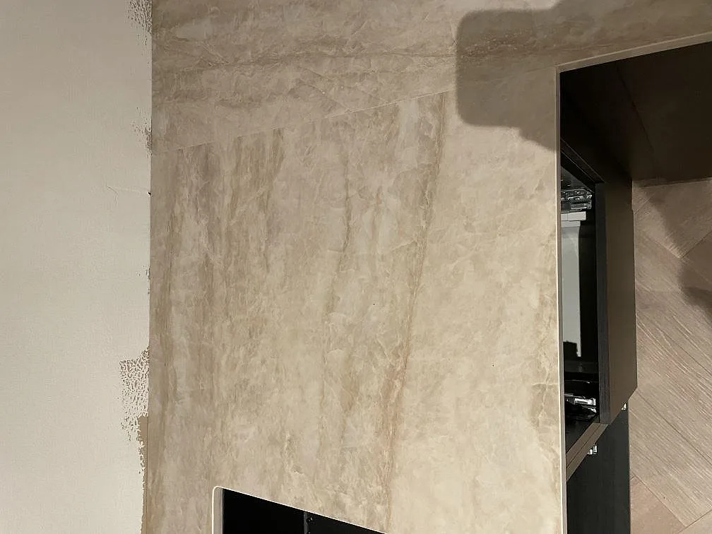 Hög stänkvägg i polerad Dekton Arga keramik bredvid en öppning i ett kök i Frillesås.