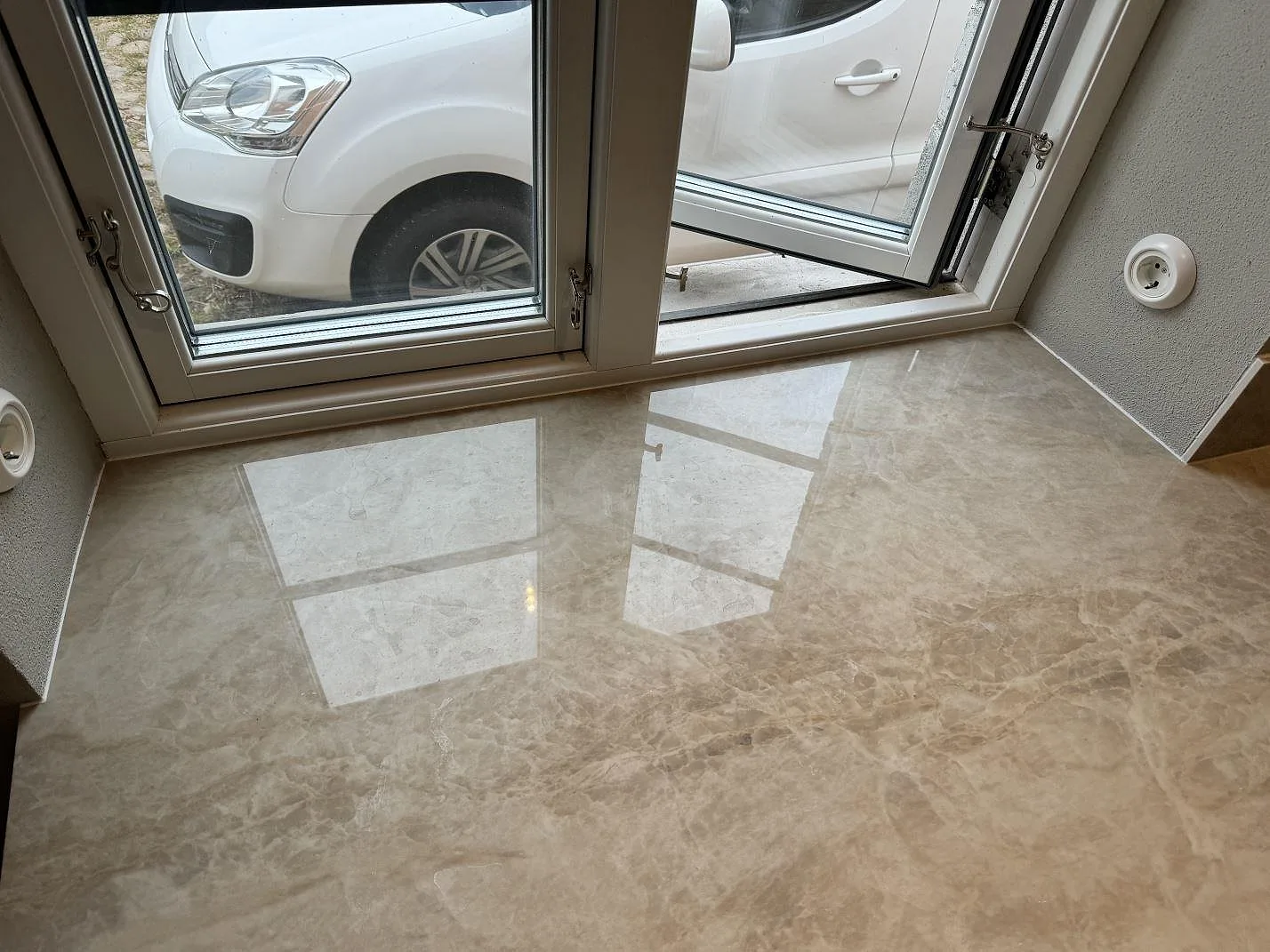 Blank köksbänkskiva i Dekton Arga under stora fönster, polerad keramik med naturstensmönster i Gärsnäs.