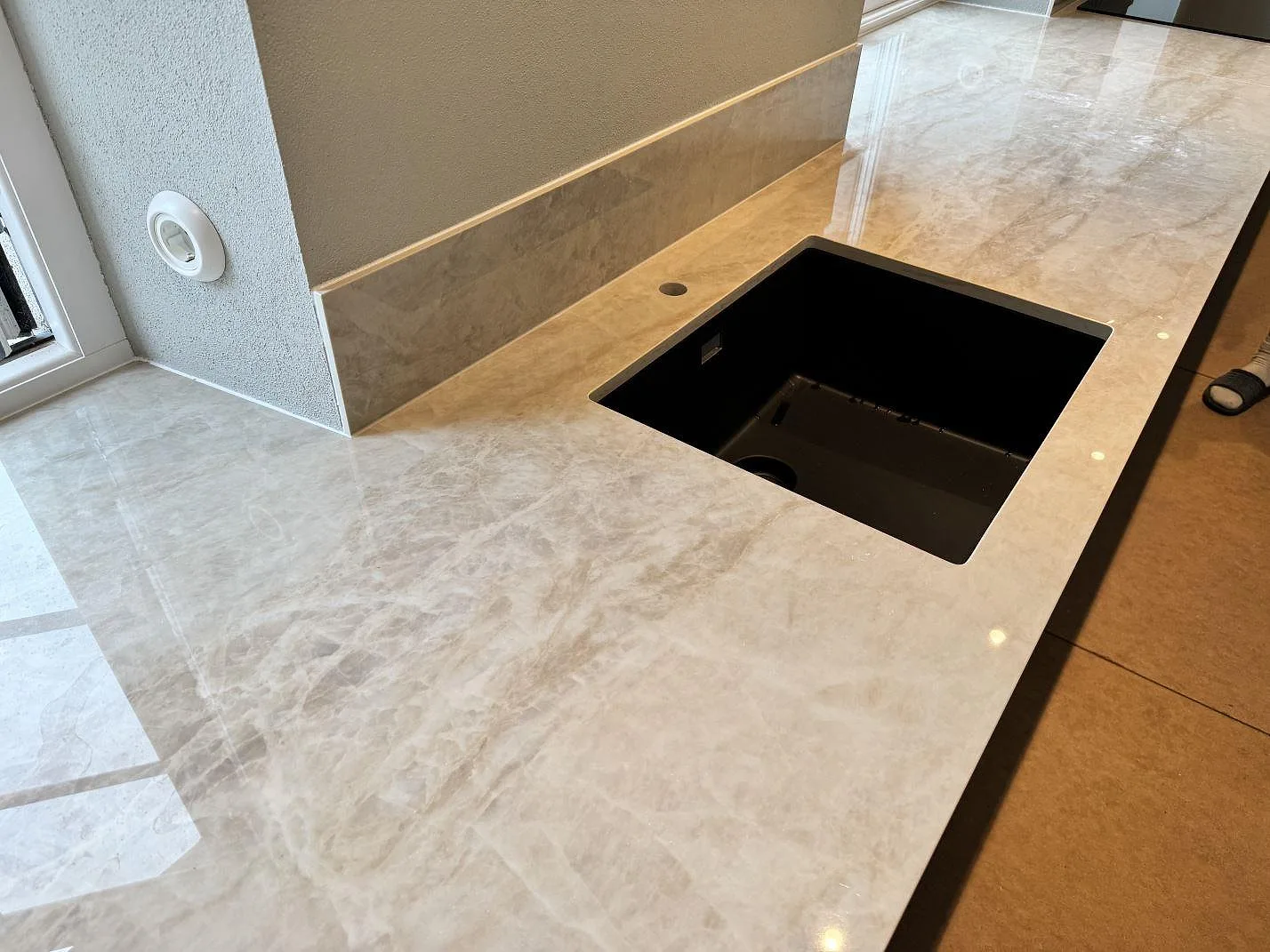 Köksbänkskiva i polerad Dekton Arga, 20 mm, med svart underlimmad diskho och stänkskydd i ett kök i Gärsnäs.