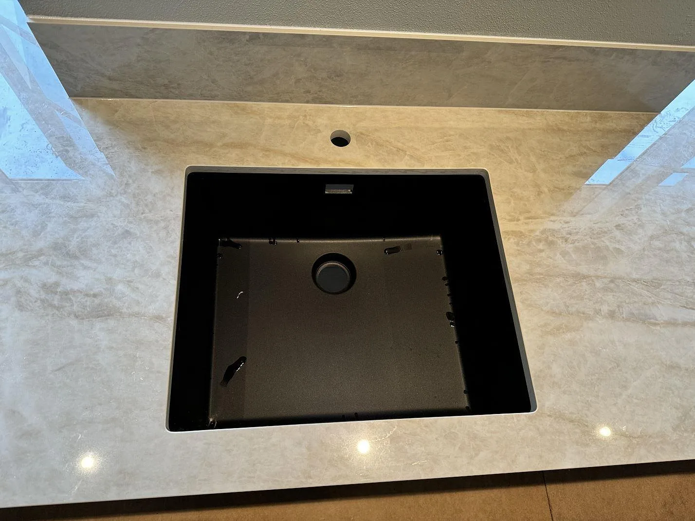 Närbild på svart underlimmad diskho i köksbänkskiva av polerad Dekton Arga i Gärsnäs.