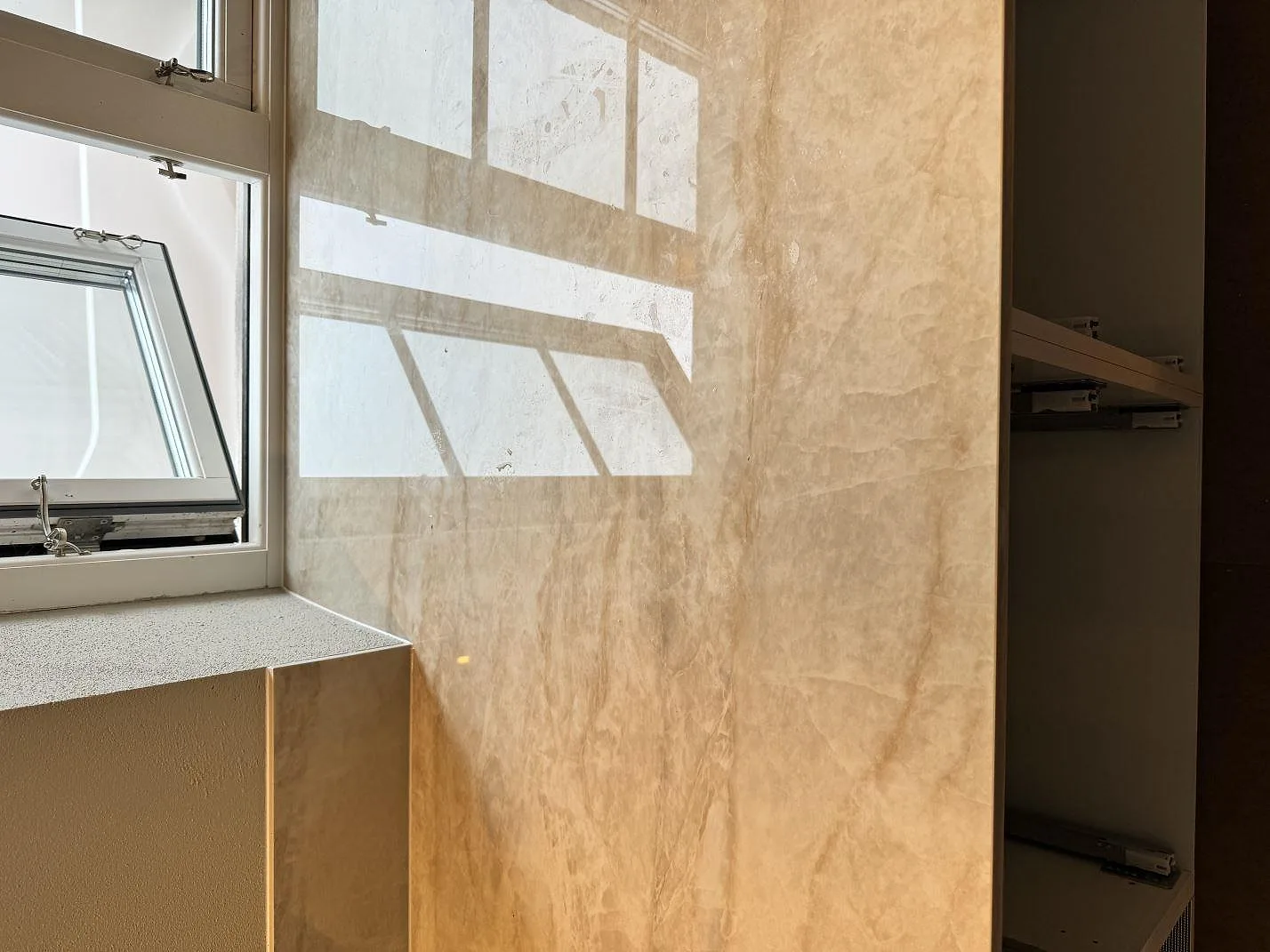 Vertikal väggbeklädnad i polerad Dekton Arga vid köksbänken och fönstret i Gärsnäs.