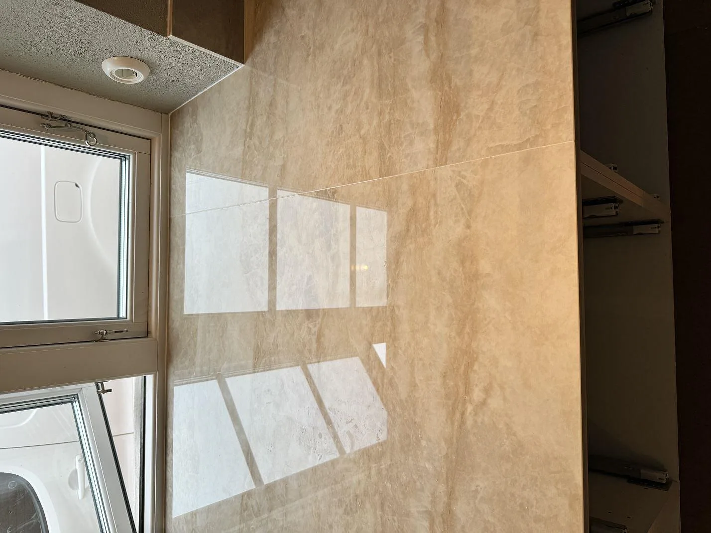 Polerad Dekton Arga som väggbeklädnad med tydlig ådring och fönsterreflektion i köket i Gärsnäs.