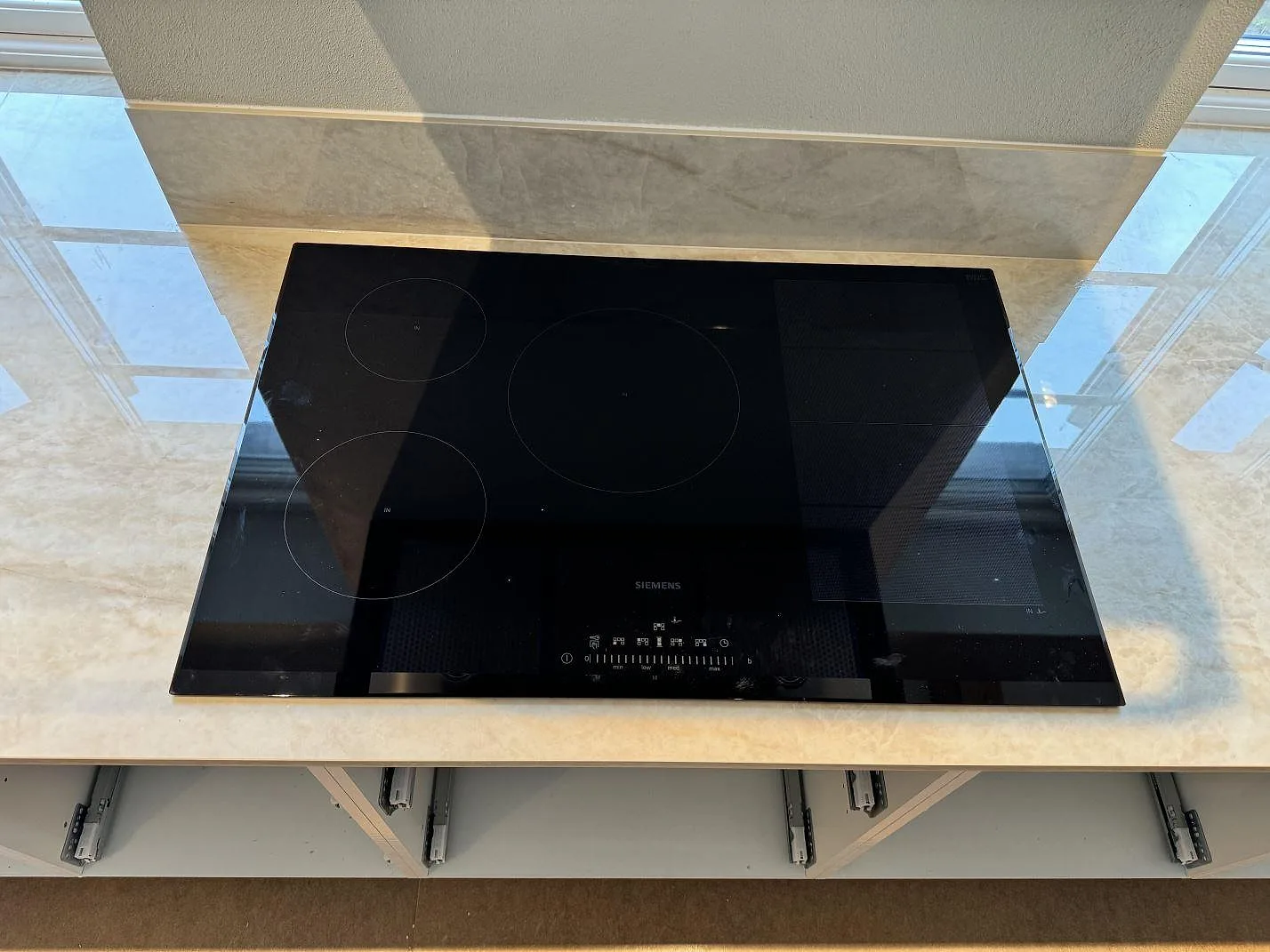 Svart induktionshäll på köksbänkskiva i polerad Dekton Arga med 8 mm stänkskydd i ett kök i Gärsnäs.