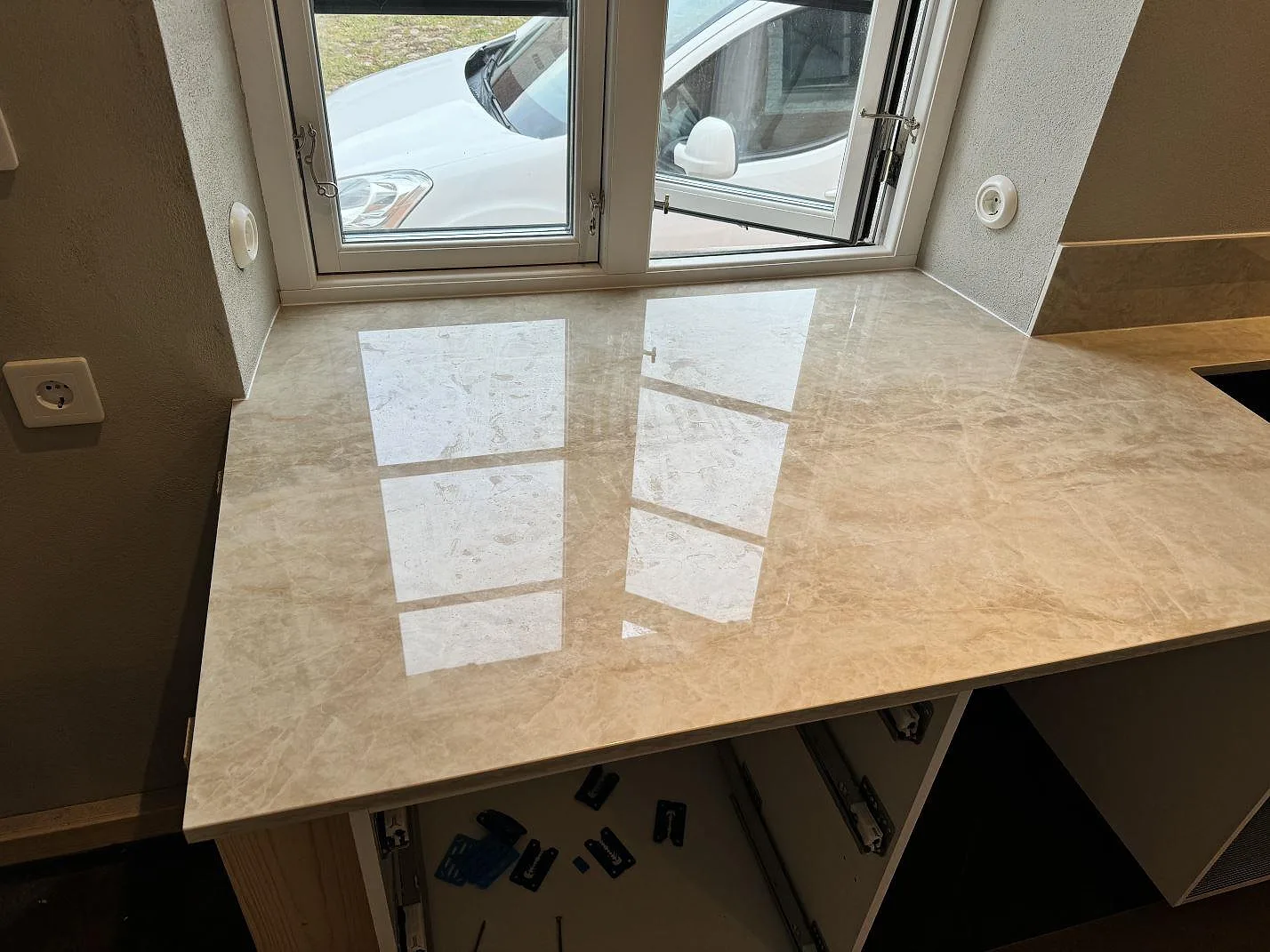 Polerad Dekton Arga som köksbänkskiva under stora fönster, med ljus ådring och öppen stomme i Gärsnäs.