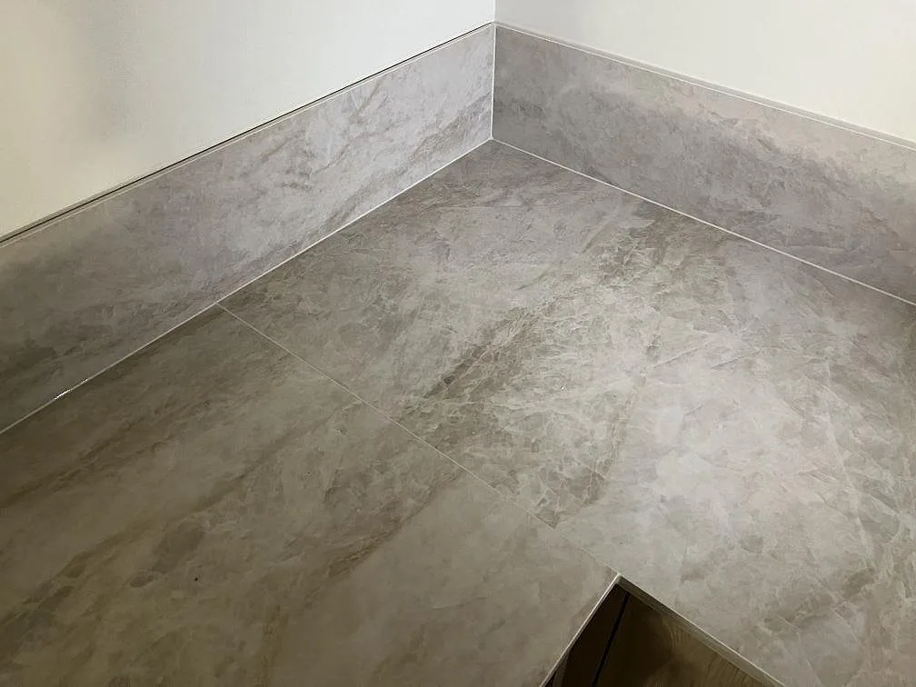 Hörndetalj av polerad Dekton Arga bänkskiva med matchande stänkskydd i ett kök i Gemla.