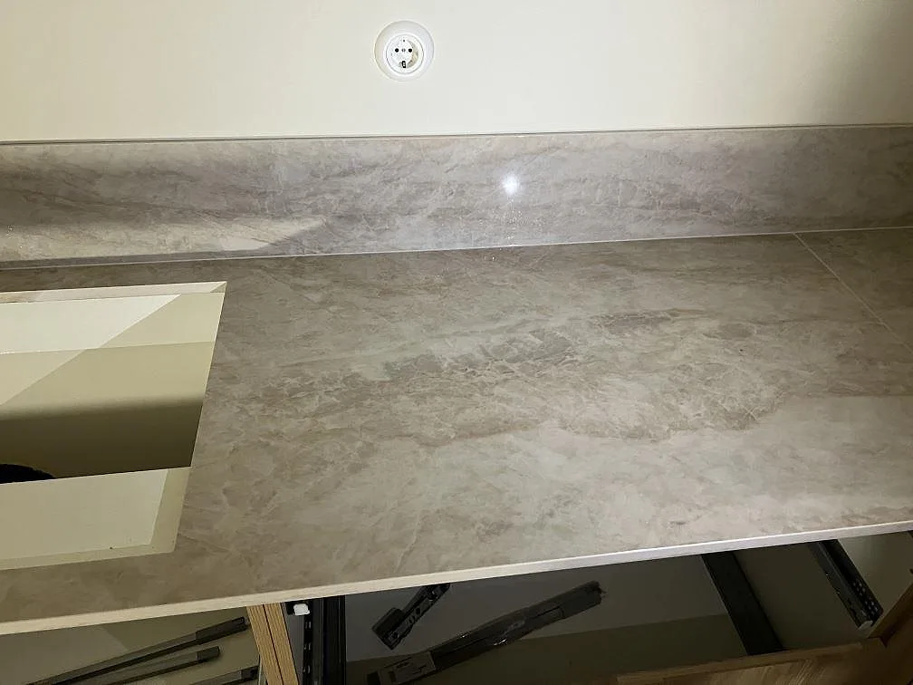 Installerad köksbänkskiva i polerad Dekton Arga med lågt stänkskydd och öppna stommar i Gemla.