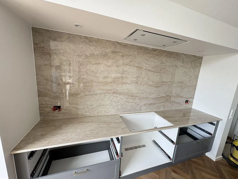 Rak köksbänkskiva i polerad Dekton Arga, keramik, med fullhöjd väggbeklädnad och förberedd hällöppning i Gentofte.