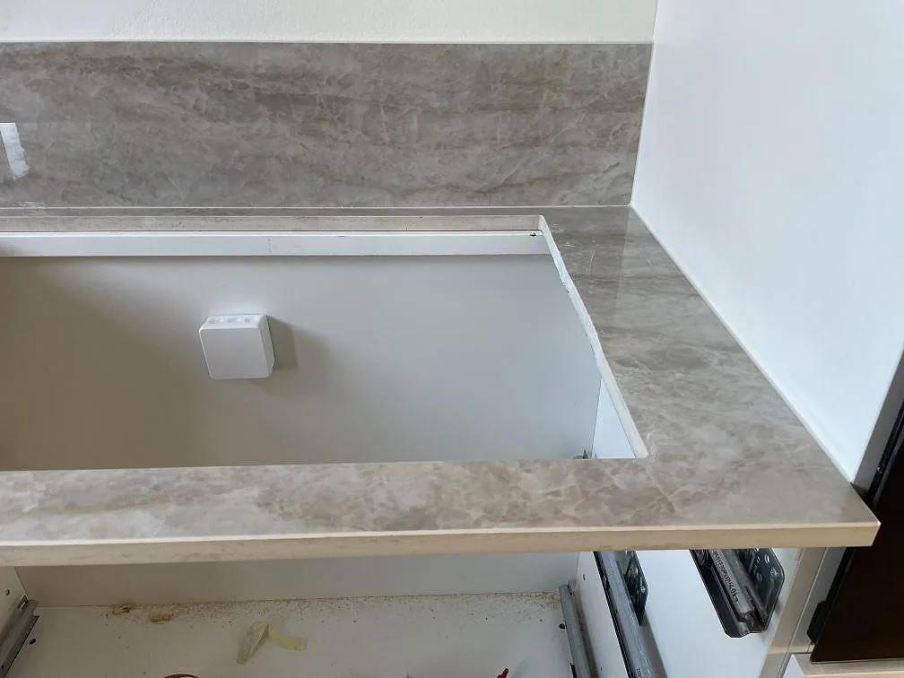 U-formad del av polerad Dekton Arga köksbänkskiva i keramik med hälluttag och 8 mm stänkskydd i Glostrup.
