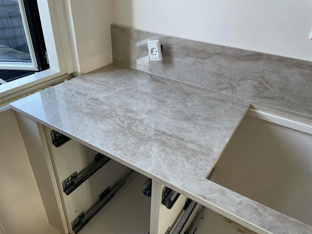 Polerad Dekton Arga bänkskiva i keramik vid fönster med 8 mm stänkskydd och utsågning för häll i Glostrup.