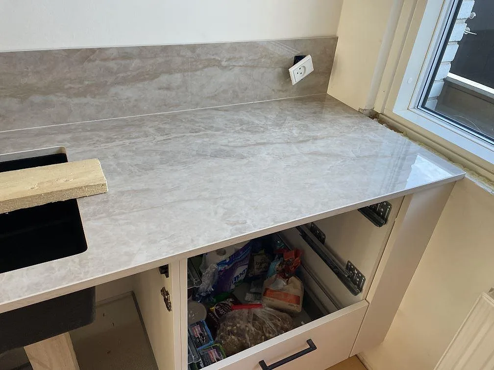 Köksbänkskiva i polerad Dekton Arga keramik vid fönster med underlimmad mörk diskho och synliga köksstommar i Glostrup.