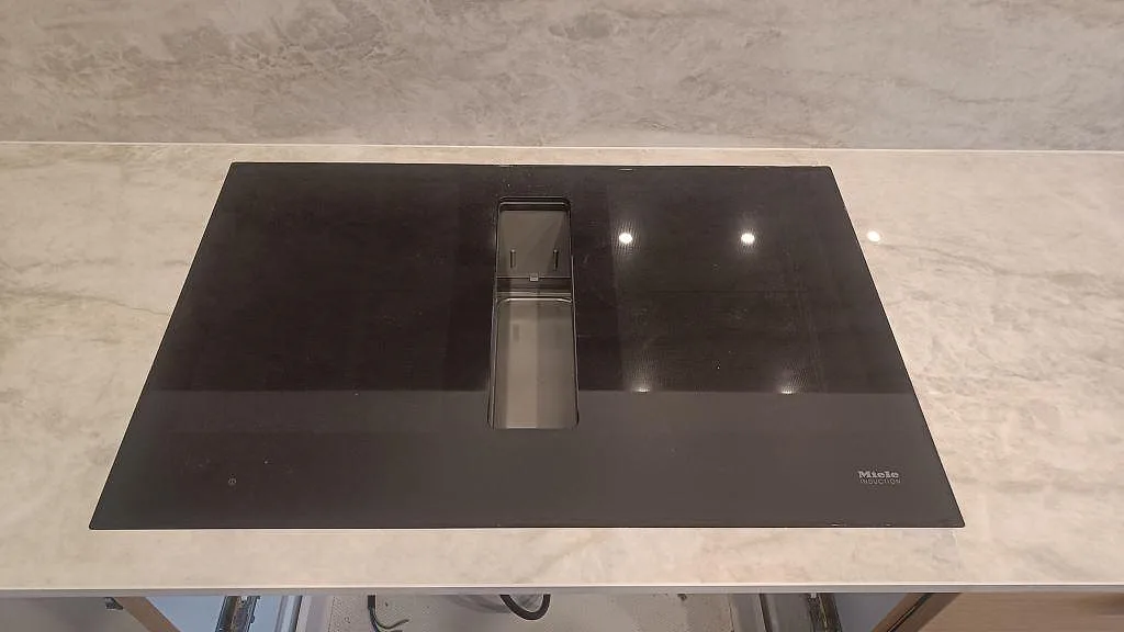 Närbild på svart induktionshäll i polerad Dekton Arga keramik med ljus ådring och blank yta i Glostrup.