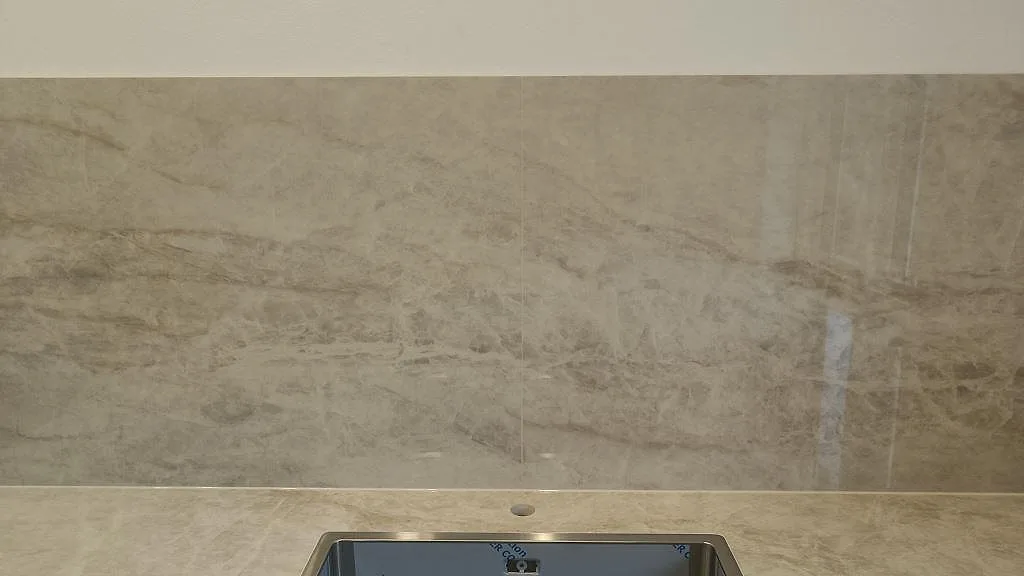 Stänkskydd i polerad Dekton Arga ovanför diskhozonen, med ådrad keramikyta i köket i Glostrup.
