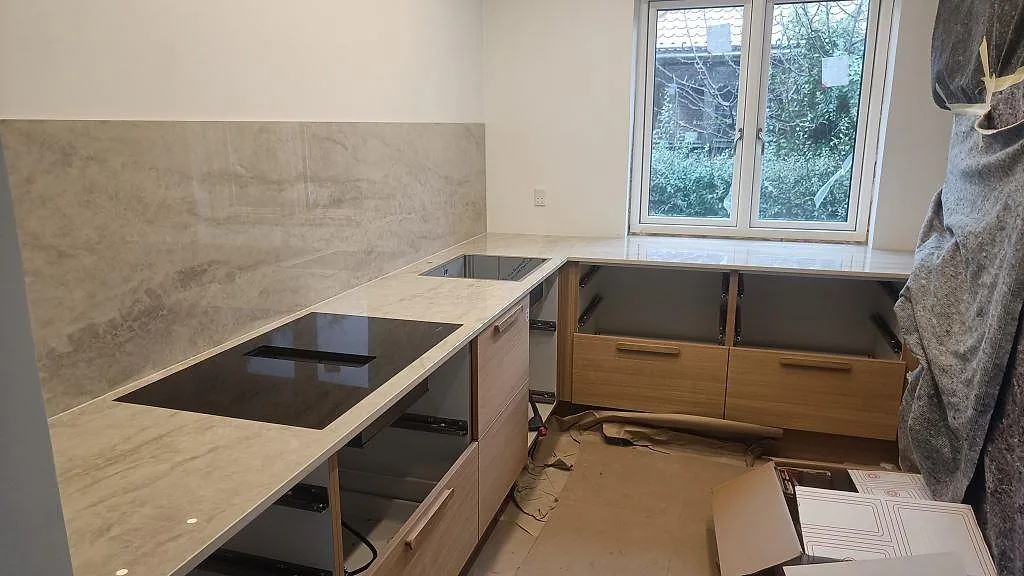 Köksbänkskiva i polerad Dekton Arga keramik med L-formad arbetsyta, induktionshäll, underlimmad rostfri diskho och stänkskydd i Glostrup.