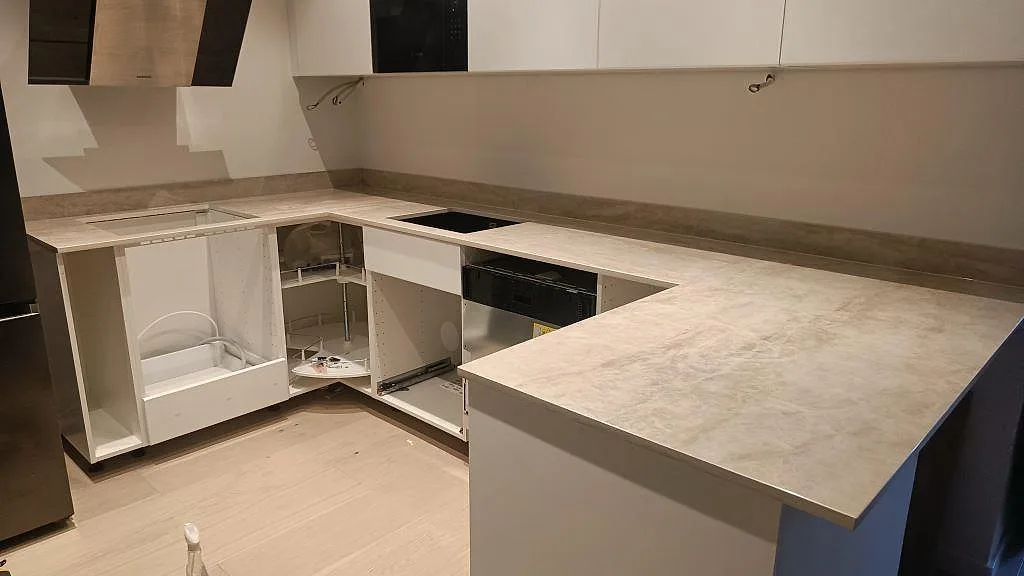 Köksbänkskiva i Dekton Arga, polerad ljus marmorlik keramik, i ett L-format kök med halvö och induktionshäll i Göteborg.