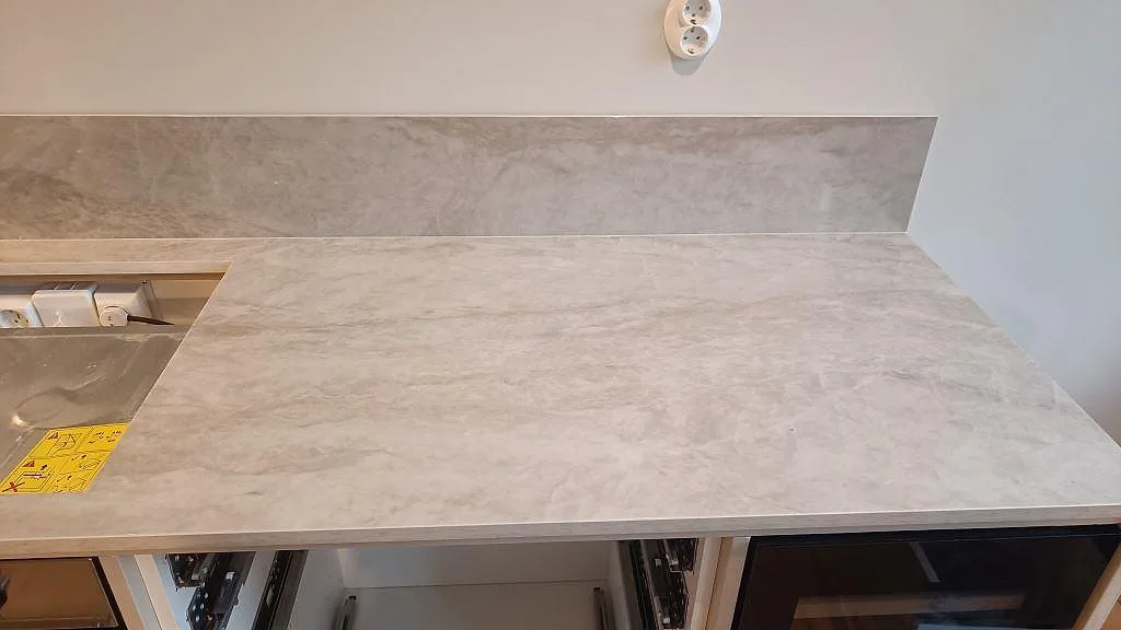 Arbetsyta i polerad Dekton Arga med 8 mm stänkskydd och öppen köksstomme under montering i Göteborg.