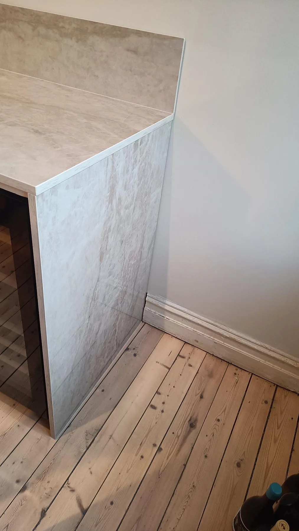 Sidopanel och bänkskiva i polerad Dekton Arga med marmorerad ådring vid köksavslut i Göteborg.
