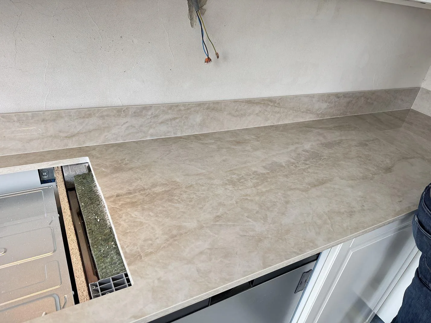 Köksbänkskiva i polerad keramik, Dekton Arga, med låg stänkkant och förberedd hällplats i Göteborg.