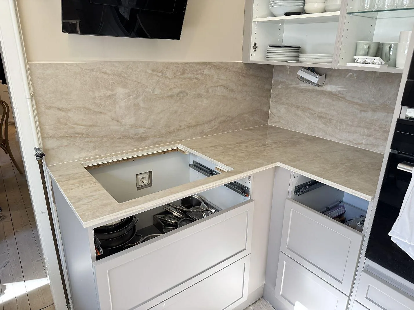 Köksbänkskiva i polerad Dekton Arga, ljus keramik med stänkskydd och hällöppning i ett kök under montering i Göteborg.
