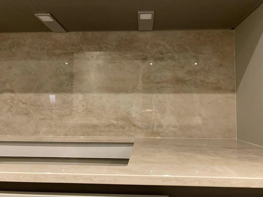 Polerad Dekton Arga väggbeklädnad och köksbänkskiva med ljus beige ådring och hällurtag i Greve.