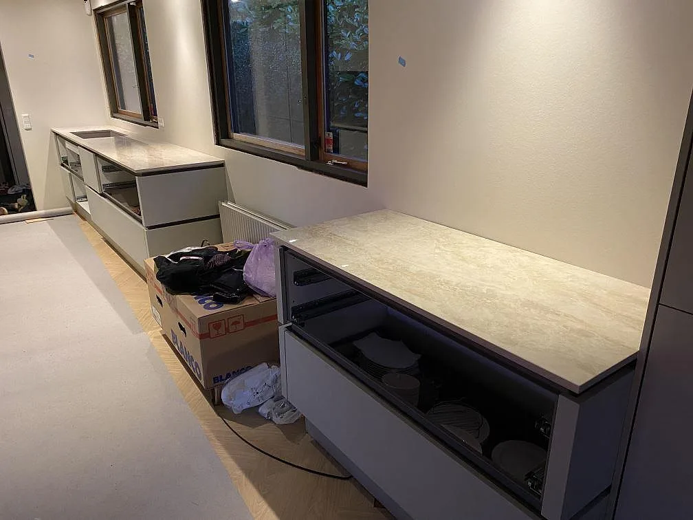 Kök under montering i Greve med två bänkytor i polerad Dekton Arga och öppna skåpstommar.