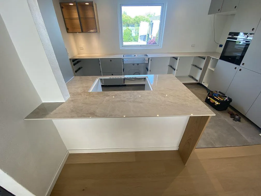 Översikt av köksbänkskiva i polerad Dekton Arga, 12 mm keramik, med bred arbetsyta och fönstersida i ett kök i Greve.
