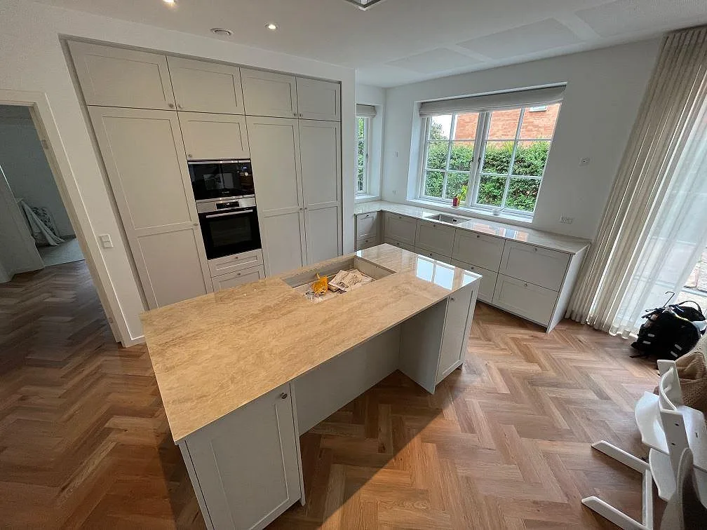Köksbänkskiva i polerad Dekton Arga-keramik, 20 mm, på köksö och bänkrad under fönster i ett ljust kök i Helsingør.