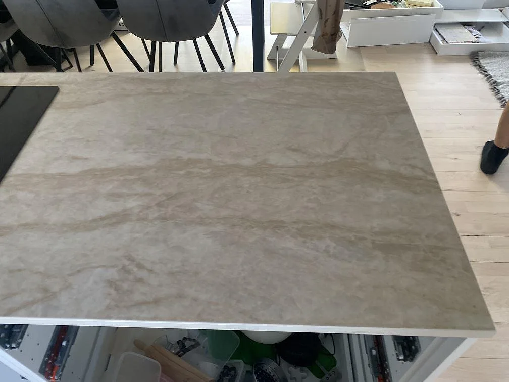Stor arbetsyta i polerad Dekton Arga på köksö med beige stenbild och öppna stommar i Hillerød.