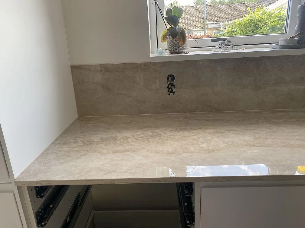 Perimeterbänk i polerad Dekton Arga med matchande stänkskydd under fönster i Hillerød.