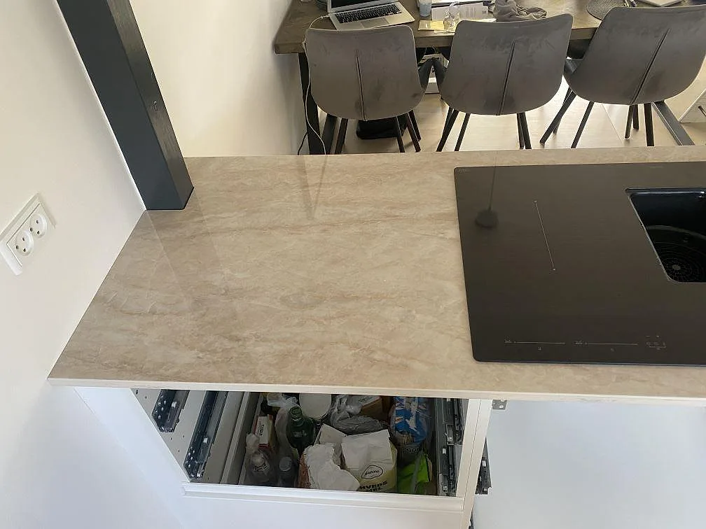 Köksö i polerad Dekton Arga med svart häll, vita stommar och öppen matplats i Hillerød.
