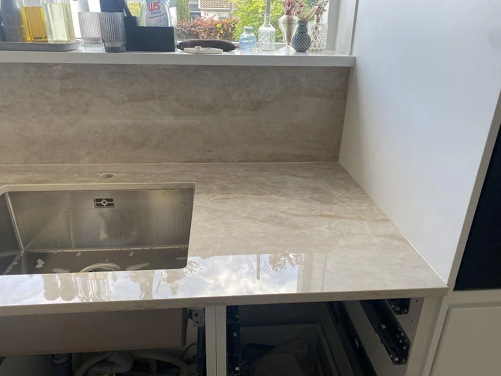 Detalj av polerad Dekton Arga runt en rostfri diskho och väggnära stänkskydd i ett kök i Hillerød.