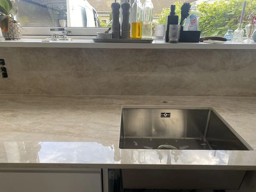 Köksbänkskiva i polerad Dekton Arga med rostfri diskho och stänkskydd under fönstret i Hillerød.